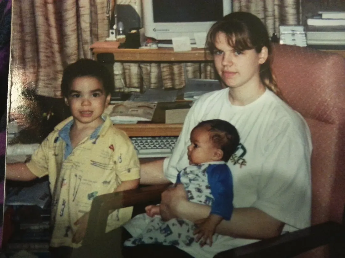 Me in a yellow patterned shirt beside Sissy, who is holding Timothy as a baby.
