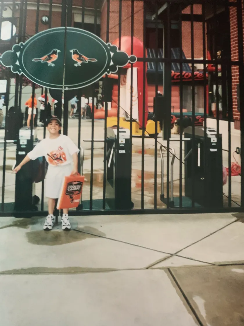 Me as a small child in a white shirt and cap, a bucket in one hand, at the gate of the Orioles' stadium in Baltimore.